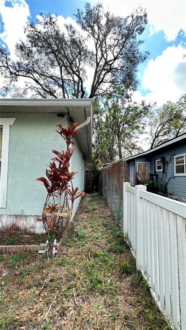 view of side of home with a fenced backyard and stucco siding