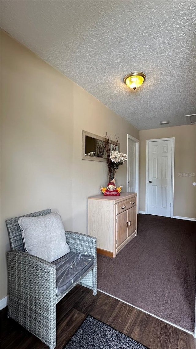 unfurnished room with baseboards, visible vents, dark wood finished floors, and a textured ceiling