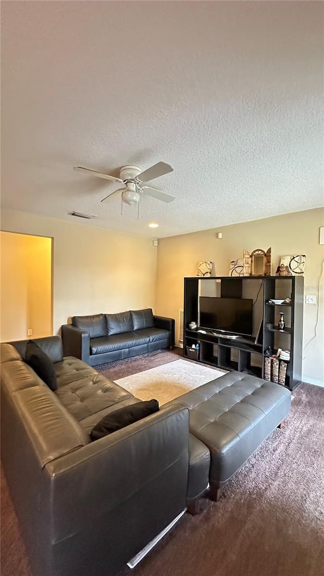 living room featuring a textured ceiling, visible vents, carpet flooring, and a ceiling fan