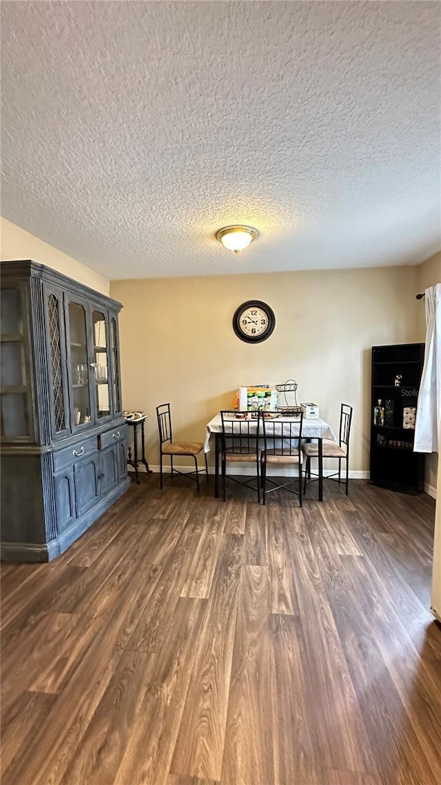 dining room with a textured ceiling, dark wood finished floors, and baseboards