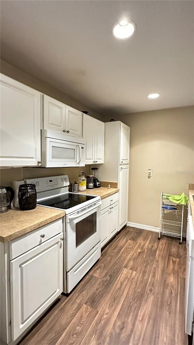 kitchen featuring white appliances, white cabinetry, baseboards, light countertops, and dark wood finished floors