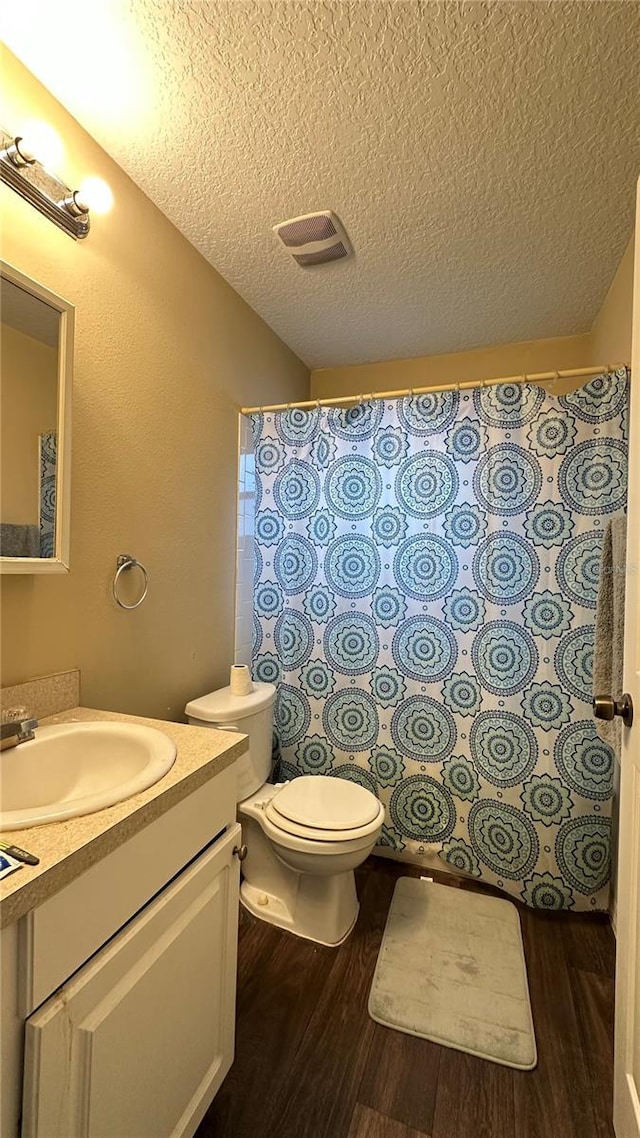 bathroom with a textured ceiling, vanity, toilet, and wood finished floors