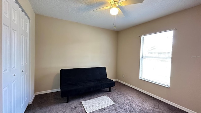 sitting room with a ceiling fan, carpet flooring, a textured ceiling, and baseboards