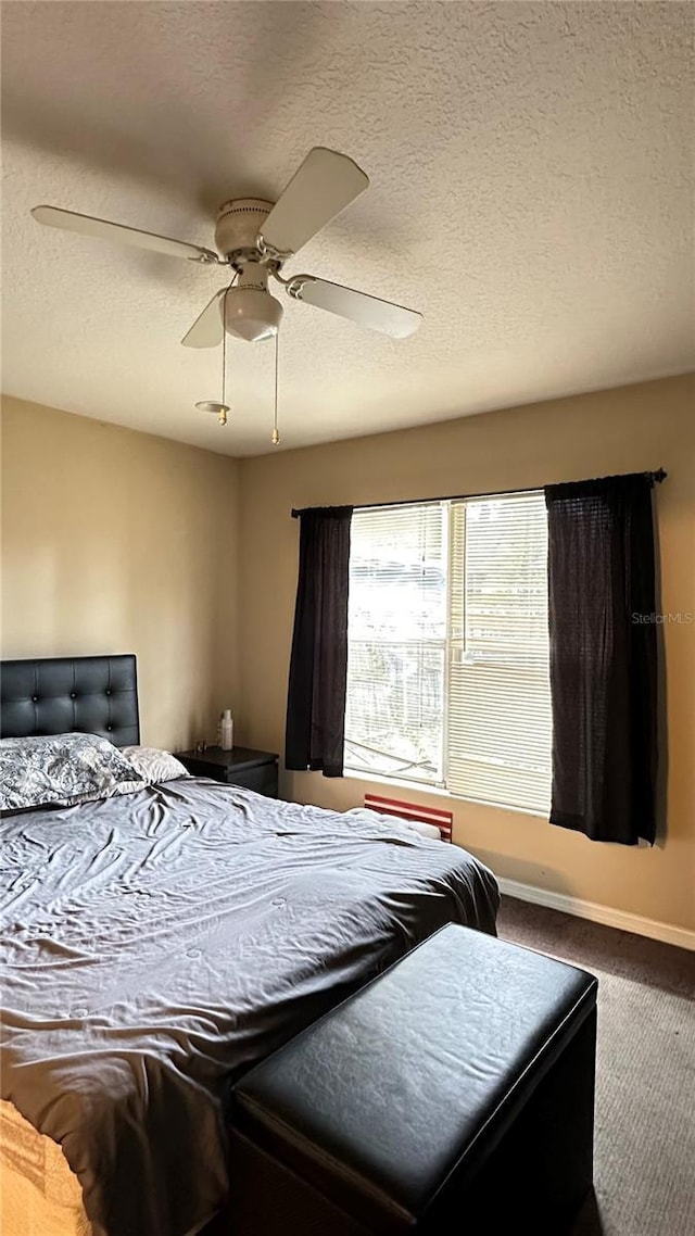 carpeted bedroom with a ceiling fan, a textured ceiling, and baseboards