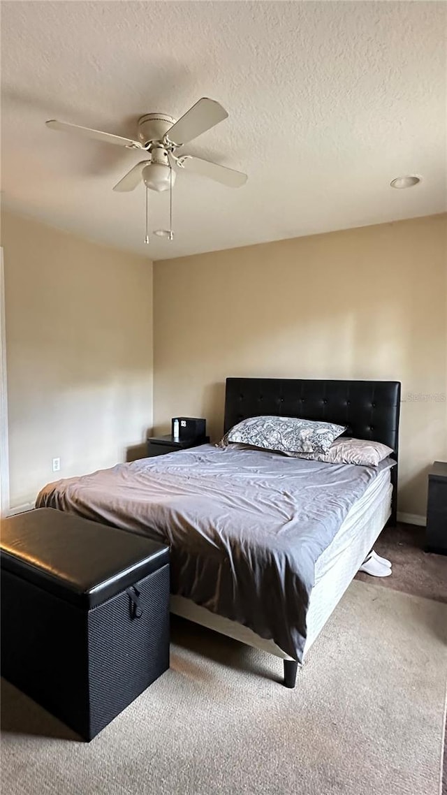 bedroom with carpet floors, ceiling fan, and a textured ceiling