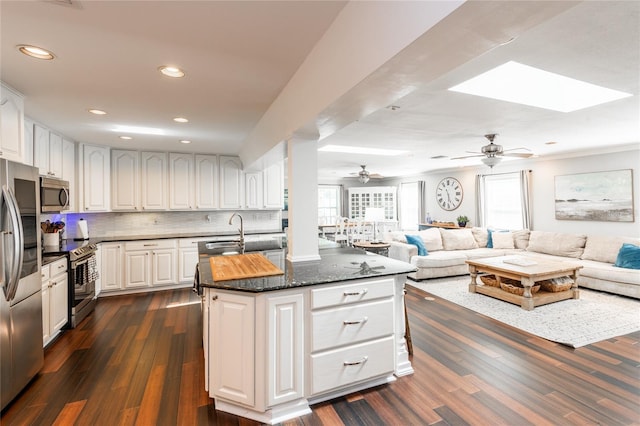 kitchen featuring white cabinets, dark wood finished floors, open floor plan, stainless steel appliances, and backsplash