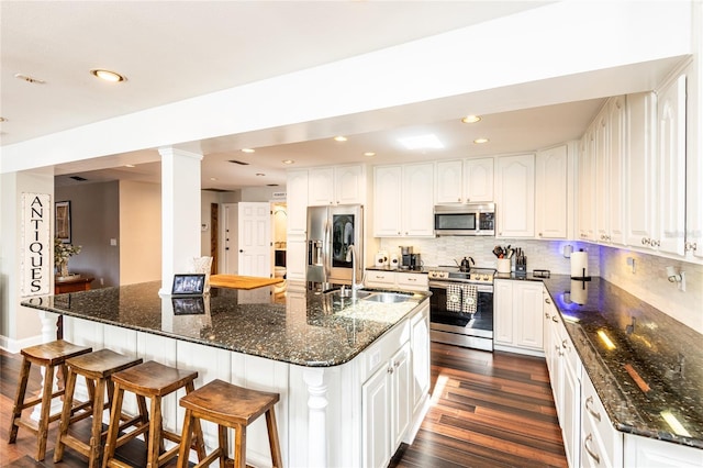 kitchen with appliances with stainless steel finishes, white cabinetry, and a kitchen island