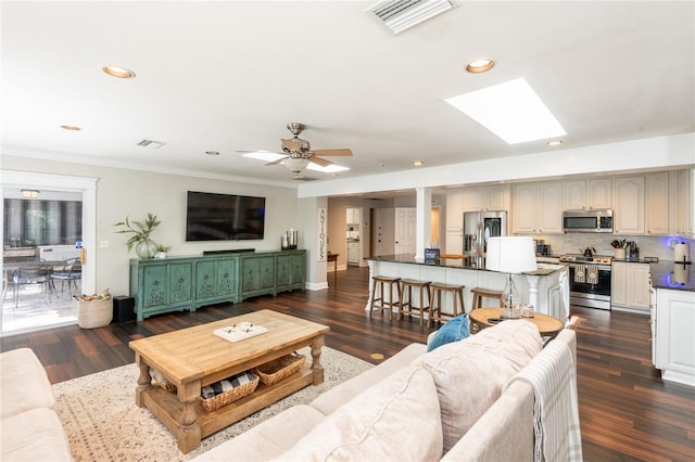 living area featuring a skylight, visible vents, dark wood-style flooring, and ornamental molding