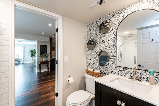 bathroom with a stall shower, visible vents, toilet, wood finished floors, and vanity