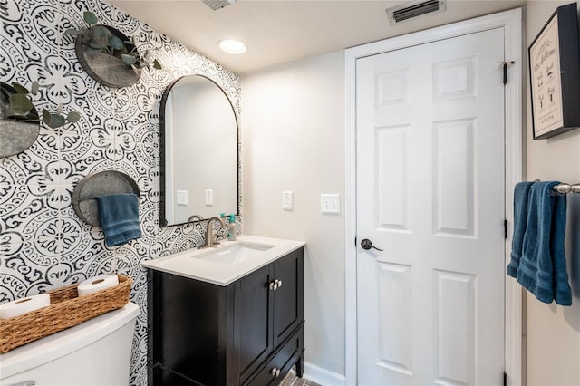 bathroom with toilet, visible vents, and vanity