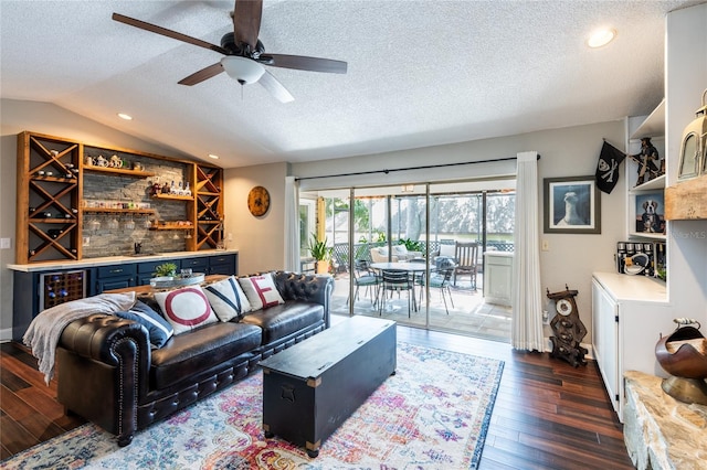 living area featuring dark wood-style flooring, lofted ceiling, ceiling fan, a textured ceiling, and bar area