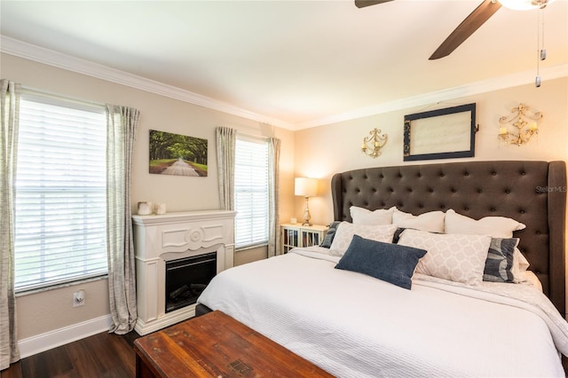 bedroom with baseboards, ceiling fan, dark wood-type flooring, crown molding, and a fireplace