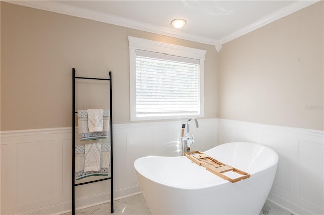 bathroom with ornamental molding, marble finish floor, wainscoting, and a freestanding bath