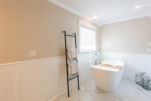 full bath featuring marble finish floor, ornamental molding, a soaking tub, and wainscoting