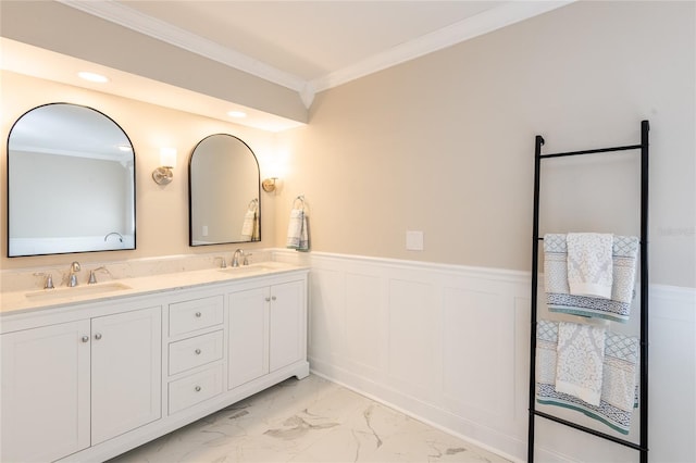 full bath featuring marble finish floor, ornamental molding, a sink, and wainscoting