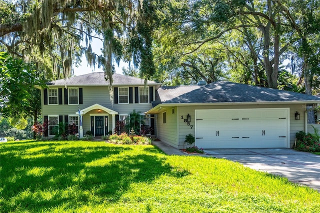 colonial house featuring driveway, a front lawn, and an attached garage