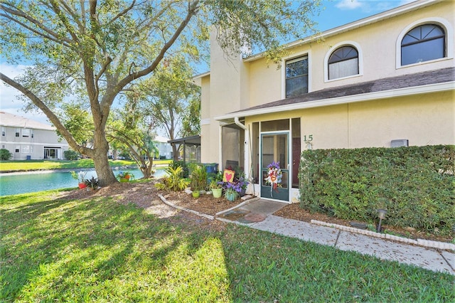 view of front of property featuring a front yard, a sunroom, and a water view