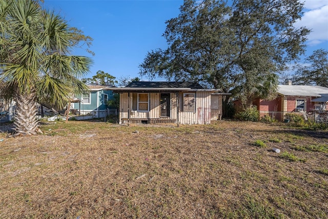 view of front of house featuring a porch, fence, and a front lawn