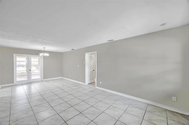 spare room featuring a notable chandelier and french doors