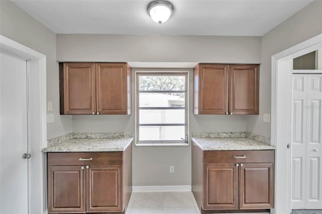 kitchen with light tile patterned floors and light stone counters