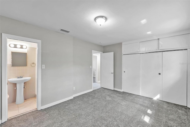 unfurnished bedroom featuring a closet, tile walls, carpet flooring, and connected bathroom