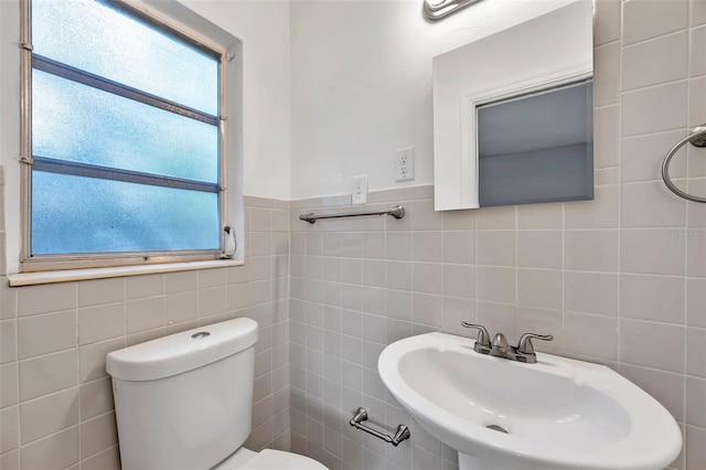 bathroom with sink, tile walls, and toilet