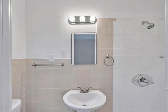 bathroom with tile walls, sink, tiled shower, and toilet