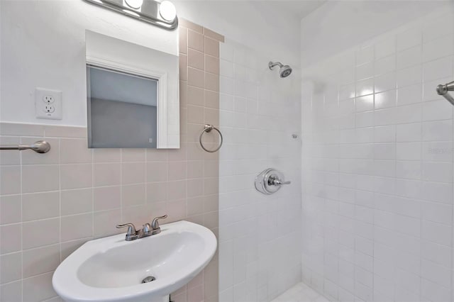 bathroom with sink, a tile shower, and tile walls