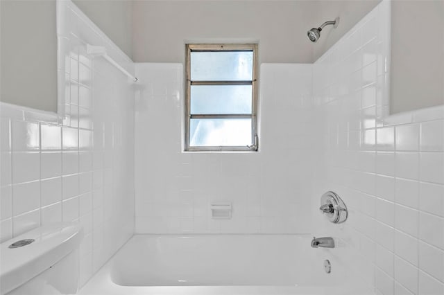 bathroom with toilet and tiled shower / bath