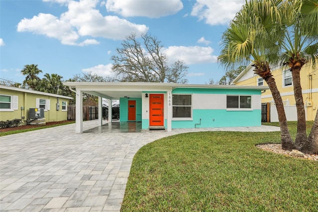 view of front facade featuring a carport, a front yard, decorative driveway, and fence