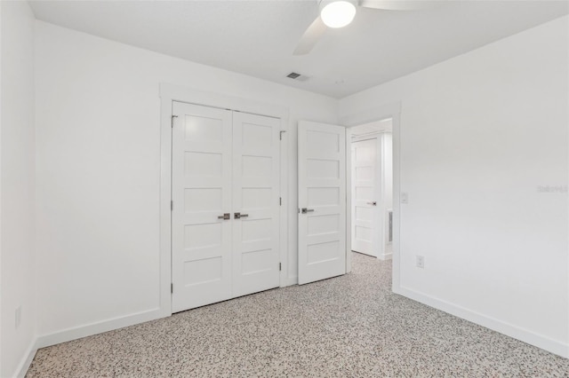 unfurnished bedroom with visible vents, baseboards, a ceiling fan, speckled floor, and a closet