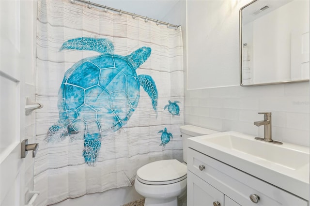 bathroom with visible vents, toilet, tile walls, and vanity