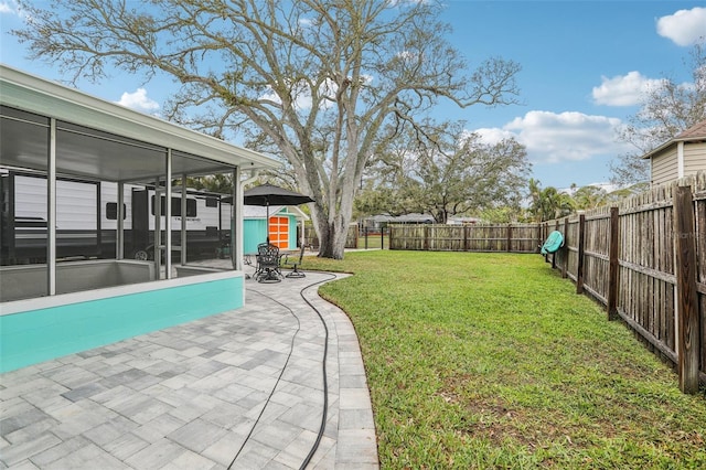 view of yard featuring a patio area, a fenced backyard, and a sunroom