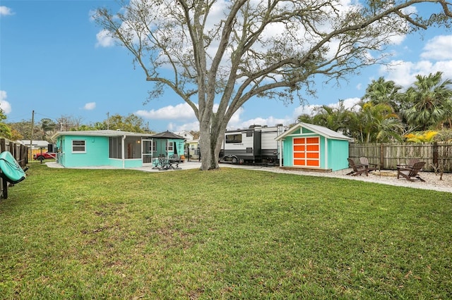 view of yard with a patio, an outdoor fire pit, an outdoor structure, fence, and a shed