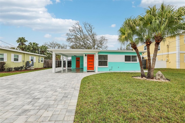 view of front of property featuring fence, a front lawn, and decorative driveway