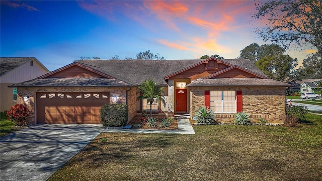 view of front of property featuring a garage, concrete driveway, brick siding, and a front lawn