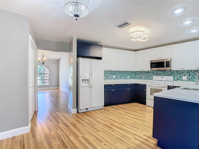 kitchen with white appliances, white cabinets, decorative light fixtures, blue cabinets, and a chandelier