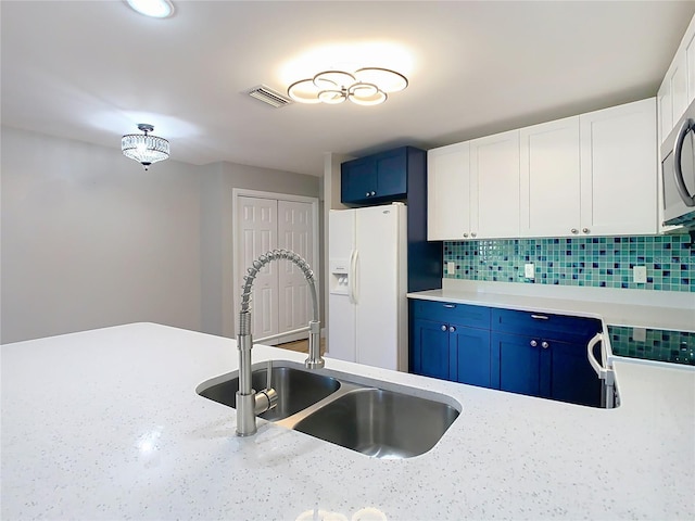 kitchen featuring white fridge with ice dispenser, blue cabinets, sink, tasteful backsplash, and white cabinets