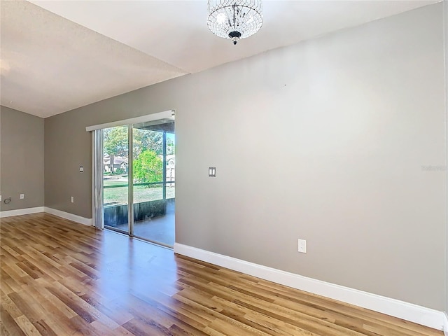 spare room with light hardwood / wood-style flooring and a chandelier