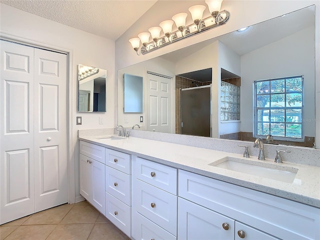 bathroom with tile patterned flooring, a textured ceiling, walk in shower, vaulted ceiling, and vanity