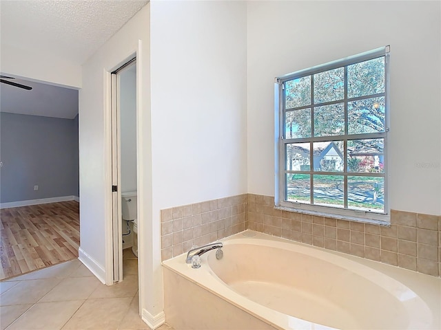 bathroom with tile patterned floors, toilet, a bathing tub, and a textured ceiling