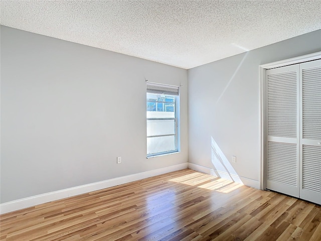 unfurnished bedroom with light wood-type flooring, a closet, and a textured ceiling