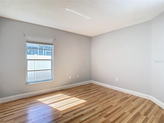 spare room featuring a textured ceiling and light hardwood / wood-style flooring