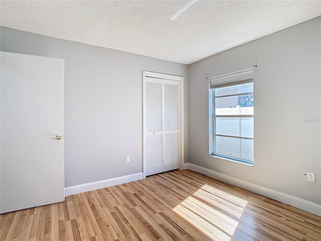 unfurnished bedroom featuring light hardwood / wood-style flooring, a closet, and a textured ceiling