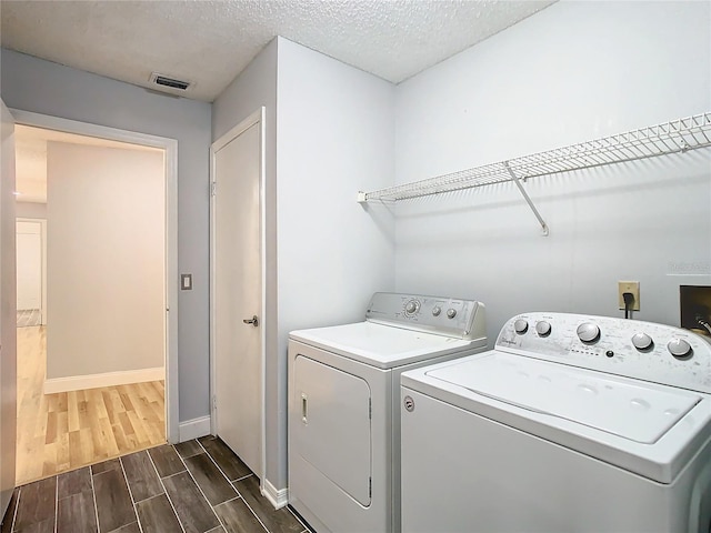 washroom with washing machine and clothes dryer and a textured ceiling