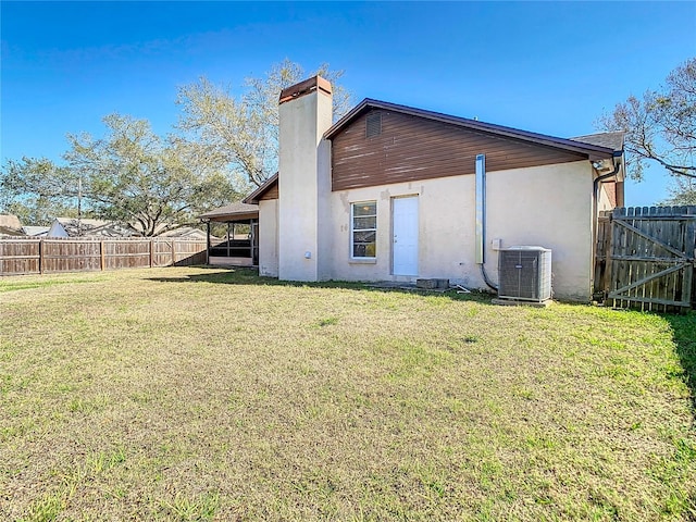 rear view of property featuring cooling unit and a lawn