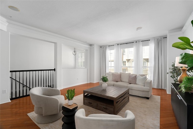 living room featuring a textured ceiling, baseboards, and light wood-style floors