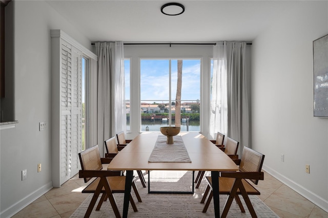 dining room with baseboards, light tile patterned floors, and a water view