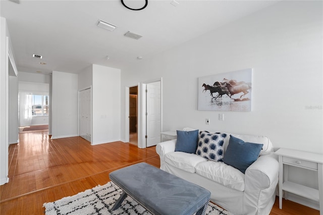 living area featuring baseboards, wood finished floors, and visible vents