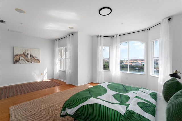 bedroom featuring light wood-style flooring, baseboards, visible vents, and multiple windows